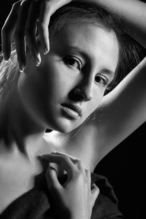 young shirtless woman cover her body on black background looking at cameraの写真素材