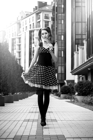 attractive young woman with lollipop in black dress posing on street, monochromeの写真素材