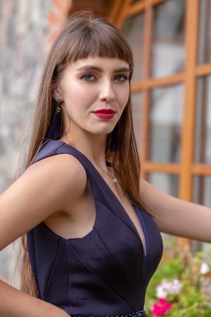 beautiful girl in blue dress near window looking at camera, smilingの写真素材