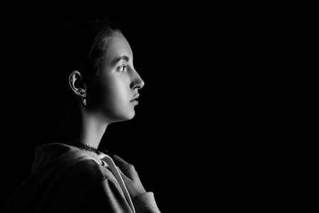 sad young female profile on black background with copy space, monochromeの写真素材
