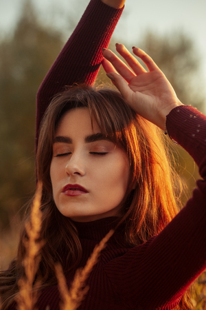 sad serious young woman in dry autumn grassの写真素材