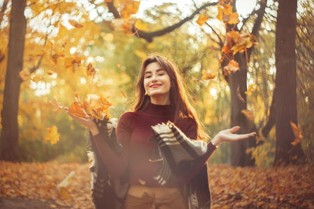 happy girl throws up autumn maple leaves in autumn forest, smilingの写真素材
