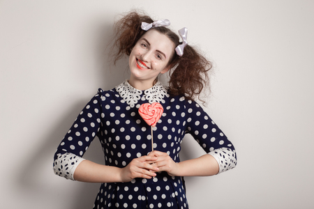 fun girl with bright makeup and red lollipop on white background smilingの写真素材