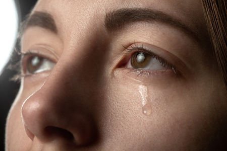 sad woman crying on black background, looking up, closeup portraitの写真素材