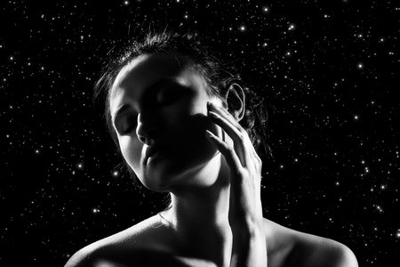 sensual woman with bare shoulders on stars background touch her face, closed eyes, monochromeの写真素材