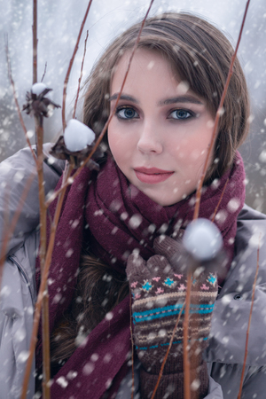 happy young woman on winter meadow under falling snowの写真素材