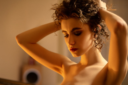sensual nude curly young woman indoors looking downの写真素材
