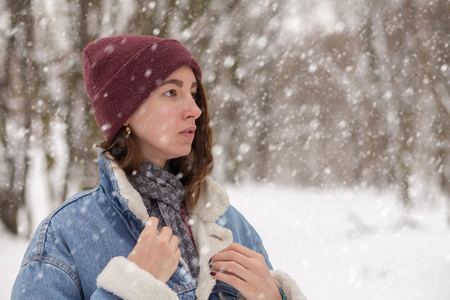 beautiful sad woman relax on winter forest under falling snowの写真素材