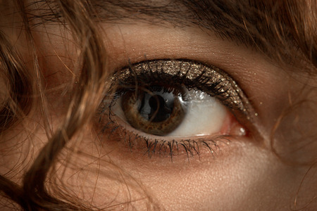 beautiful female eye with luxury makeup and curl hair looking at cameraの写真素材