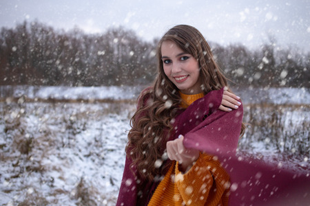 woman walking on winter meadow under falling snow smilingの写真素材