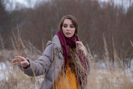 freezing young woman on winter meadow looking at camera