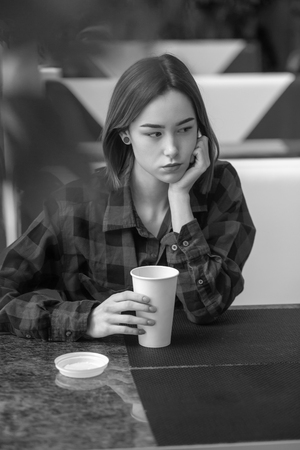 sad pensive young woman sitting in cafeの写真素材