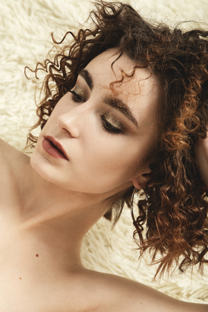 sensual beautiful serious young curly woman lying, closeup portraitの写真素材
