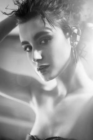 sensual beautiful serious young woman standing, closeup portrait, profile view, looking at camera, monochromeの写真素材