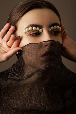 young woman with black veil and luxury makeup on gray backgroundの写真素材