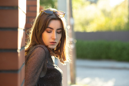 beautiful serious stressed luxury young woman in sunlight on street looks down