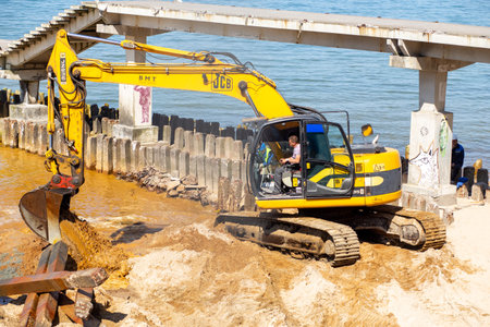 SVETLOGORSK, RUSSIA - MAY 22, 2019: excavator working on sand sea coast at Baltic sea near Svetlogorsk, Russiaのeditorial素材