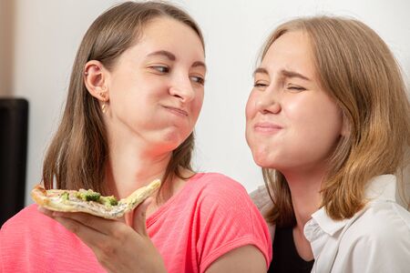 two happy girls lesbians eats pizza laughing
