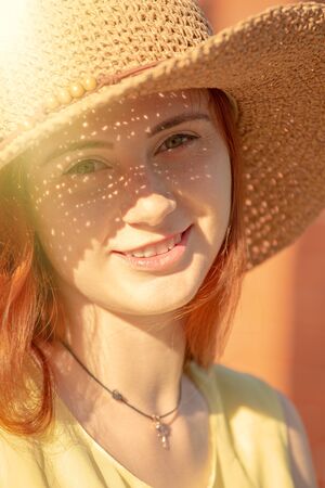 pretty red hair girl in sun hat looking at camera, smiling, toned imageの写真素材