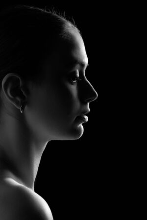 profile of young pensive woman on black background, monochromeの写真素材