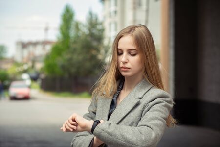 blond young woman looking on smartwatch on her wrist