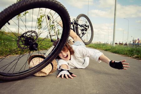 girl fell from the bicycle, lies on asphalt shouts