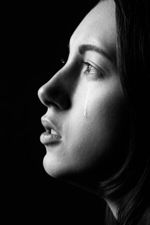 sad woman crying, looking aside on black background, closeup portrait, profile view, monochromeの写真素材