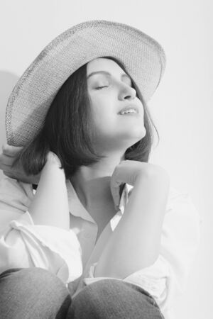 happy young woman in sunhat under sunlight closed eyes relax, monochromeの写真素材