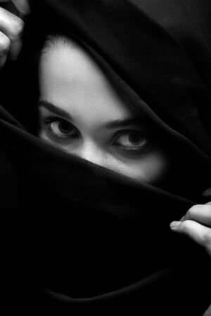serious beautiful young woman with black headscarf cover her face, looking at camera, luxury makeup, monochromeの写真素材