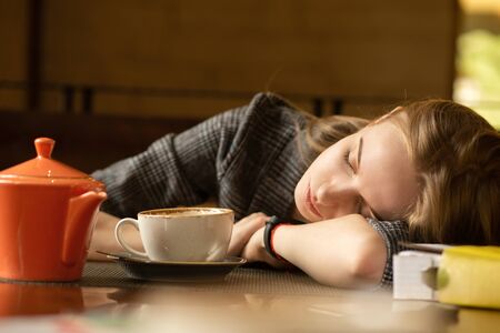 young blonde with a teapot in cafe lying on table, longs misses, dreams, sleepingの写真素材