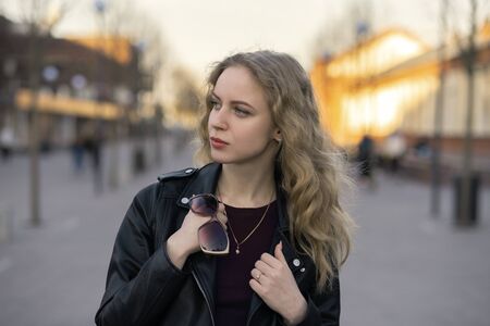 sad serious blond woman in leather coat looking asideの写真素材