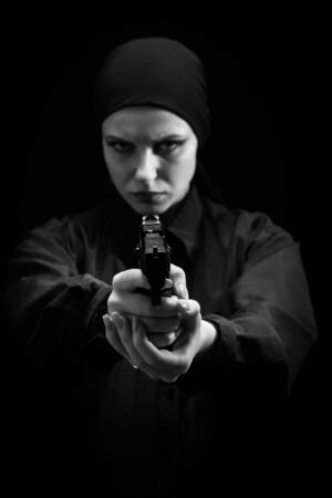 serious girl with gun aiming at camera on black background, monochromeの写真素材