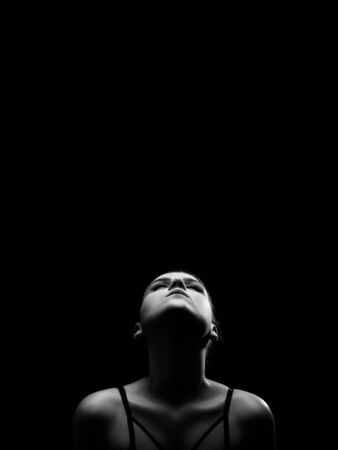 beautiful young bared woman posing sensually holding head up on black background with copy space, monochromeの写真素材