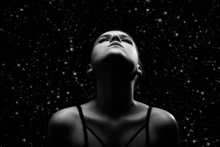 beautiful young bared woman posing sensually holding head up on stars background with copy space, monochromeの写真素材
