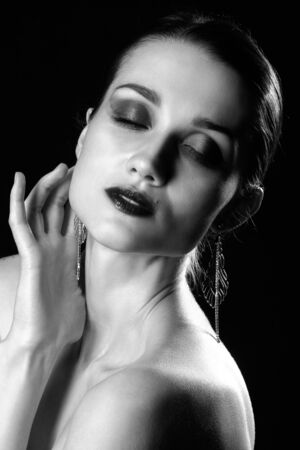young beautiful woman posing sensually on black background, closed eyes, cover her body, monochromeの写真素材