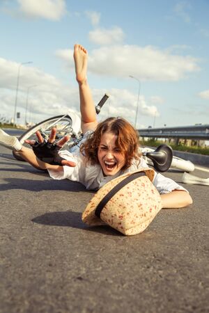 girl fell from the bicycle, lies on asphalt shoutsの写真素材