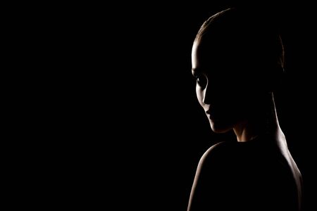 beautiful young woman with luxury makeup looking back over her bare shoulder, black background with copy spaceの写真素材