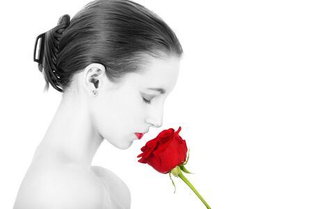 beautiful young woman smells red rose, natural beauty makeup and bare shoulders on white background profile viewの写真素材