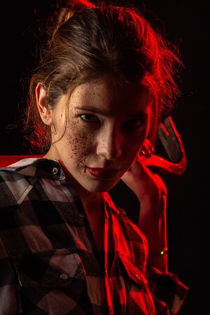 serious young bloody woman with crowbar in dark looking at camera toned imageの写真素材