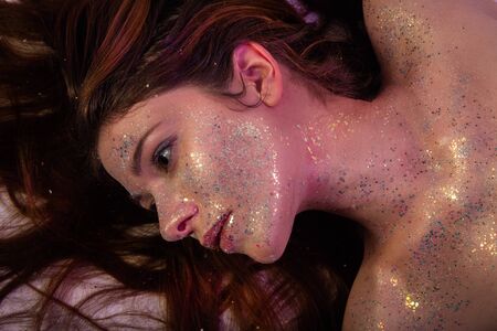 luxury young bare woman with shiny cosmetics lying looking asideの写真素材