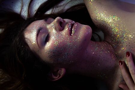 luxury young bare woman with shiny cosmetics lying with closed eyesの写真素材