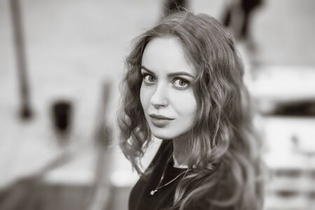 serious beautiful blond curly young woman looking back, standing on escalator, monochrome