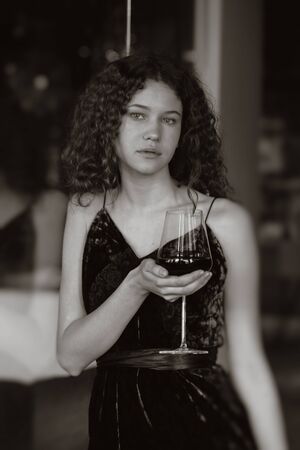 serious single luxury beautiful woman with wine standing near mirror, looking at camera, monochromeの写真素材