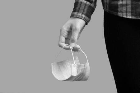 female hand with protective medical mask on gray background closeup viewの写真素材