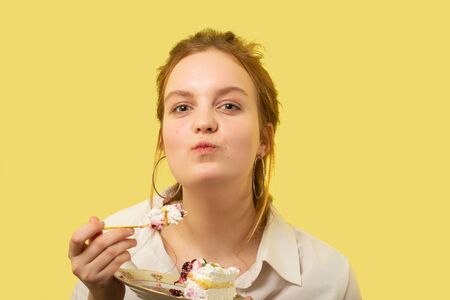 fun pretty curly red hair girl with sweet dessert on yellow backgroundの写真素材