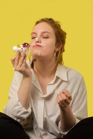 fun pretty curly red hair girl with sweet dessert on yellow backgroundの写真素材