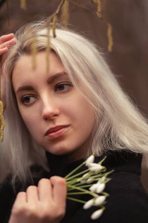 young blond woman with snowdrop bouquet at spring timeの写真素材