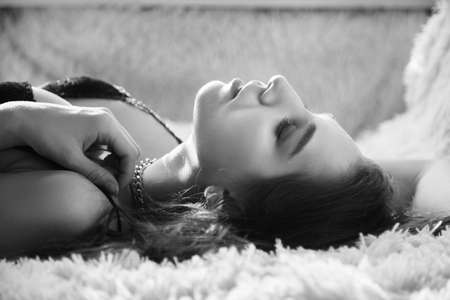 sensual beautiful woman lying in sunlight with blinds shadows, dreaming, monochromeの写真素材
