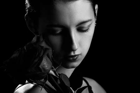 beautiful young woman with rose, natural beautiful makeup with closed eyes on a black background, monochromeの写真素材