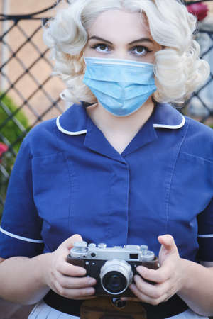 young blond woman in medical mask with photo camera